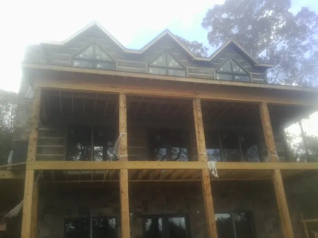 Dormers and porch framing on a large log home under construction — Roof Coating work by our crew in Edgeley