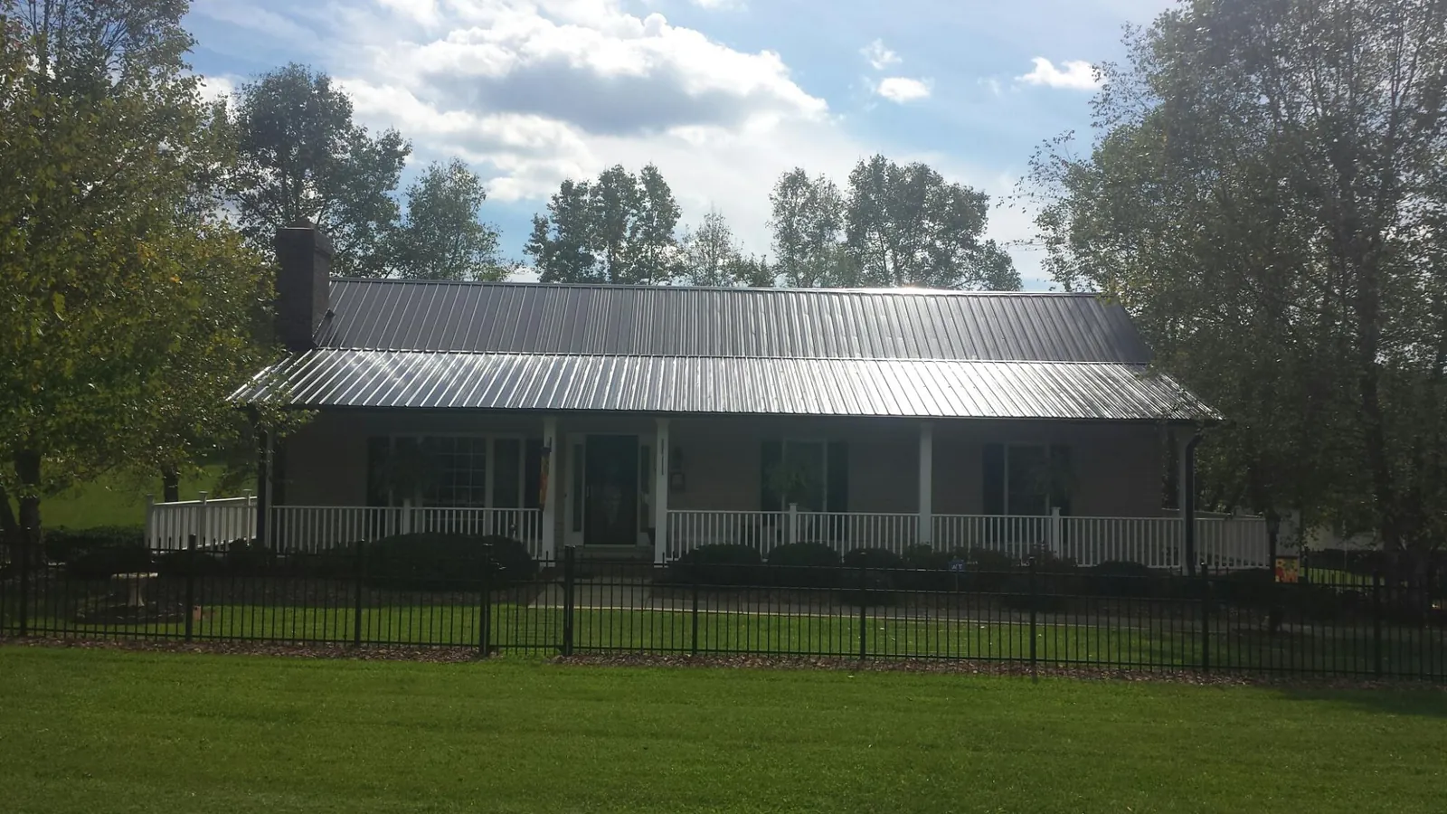 Gray metal roof on a brick ranch with a full width front porch — Gutter Guard Installation work by our crew in Edgeley